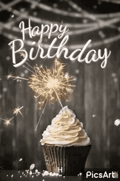 A Cupcake With Whipped Cream And A Sparkler On Top Of It . GIF