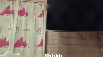 A Curtain With Sailboats And Steering Wheels Hangs Next To A Flat Screen Tv GIF