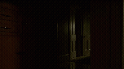 A Dark Hallway With A Few Dressers And A Door GIF