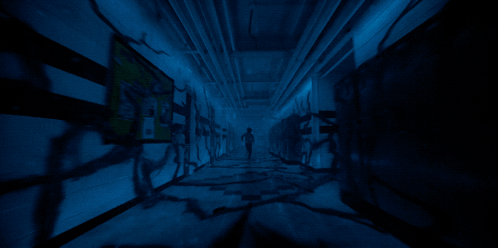 A Dark Hallway With A Sign On The Wall That Says " Emergency Exit " GIF