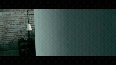 A Dark Room With A Brick Wall And A Lamp On A Table GIF