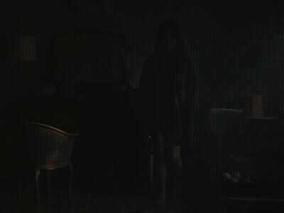 A Dark Room With A Chair And A Lamp On GIF