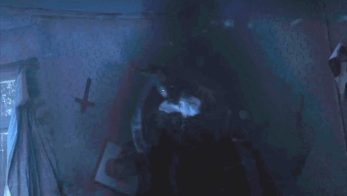 A Dark Room With A Cross On The Wall And A Picture On The Wall GIF