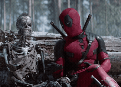 A Deadpool Sitting Next To A Skeleton In The Snow GIF