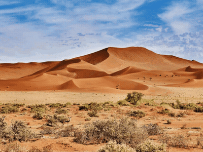 A Desert Landscape With Sand Dunes And A Blue Sky GIF