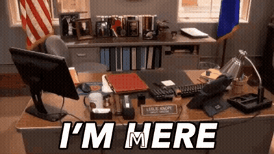 A Desk With A Computer And A Sign That Says I 'M Here On It GIF