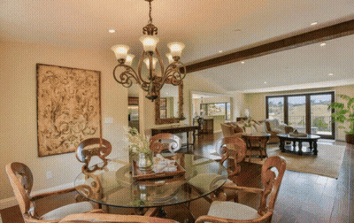A Dining Room With A Round Glass Table And Chairs And A Chandelier GIF