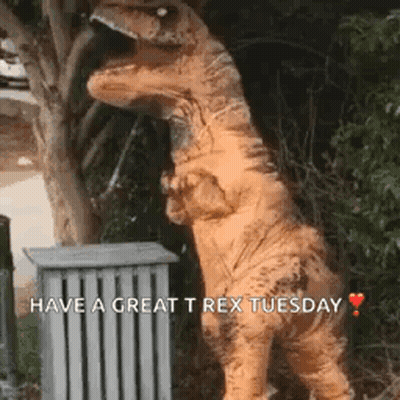 A Dinosaur In A T-Rex Costume Is Standing Next To A Trash Can And A Tree . GIF