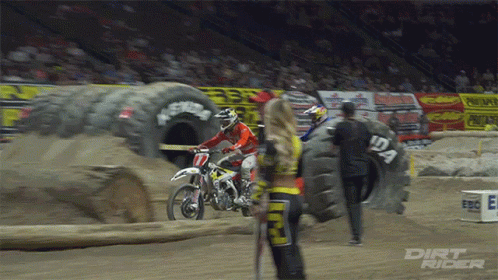 A Dirt Rider Is Standing Next To A Tire That Has The Number 12A On It GIF