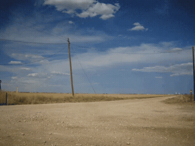 A Dirt Road Going Through A Field With Telephone Poles GIF