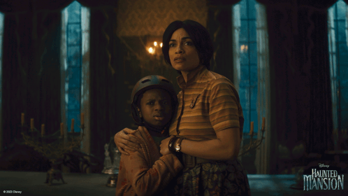 A Disney Haunted Mansion Poster With A Woman Hugging A Boy GIF