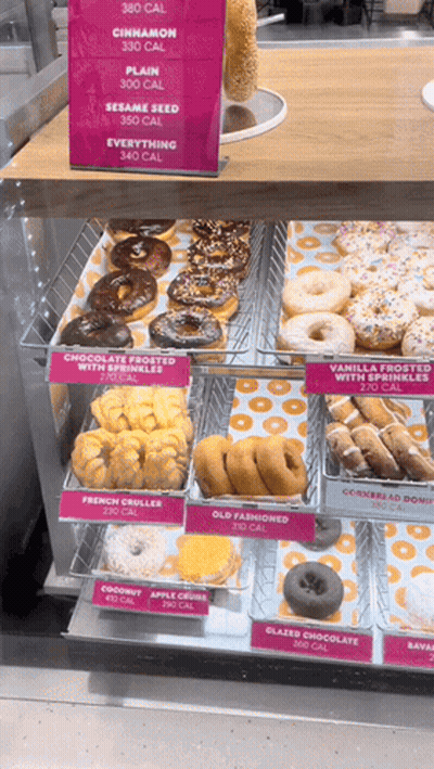 A Display Case Of Donuts With A Sign That Says 360 Calories On It GIF