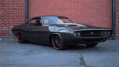A Dodge Challenger Is Parked In Front Of A Brick Building GIF