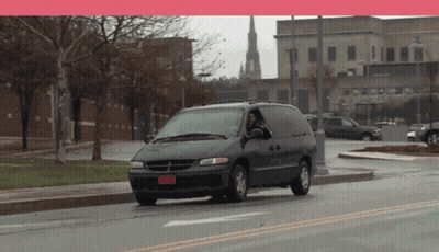 A Dodge Minivan Is Driving Down A Street With A Red License Plate That Says Rnm828 GIF