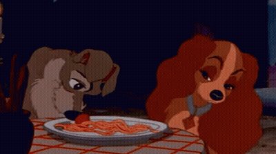 A Dog And A Woman Are Sitting At A Table Eating Spaghetti . GIF