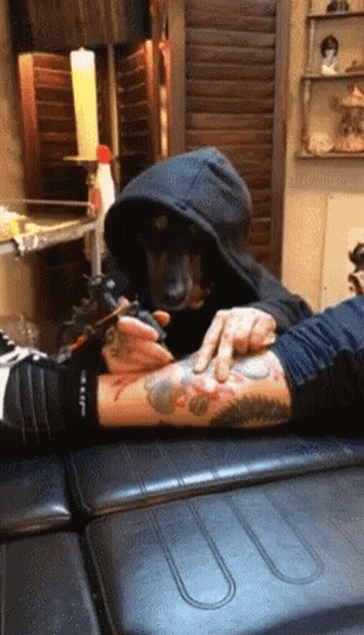 A Dog Is Getting A Tattoo On Someone 'S Arm GIF