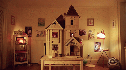 A Doll House Sits On A Wooden Table In A Bedroom GIF