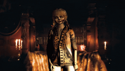 A Doll In A Leopard Print Shirt Stands In A Dark Room With Candles GIF