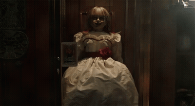 A Doll In A White Dress With A Red Rose Around Her Waist Is Standing In A Doorway GIF