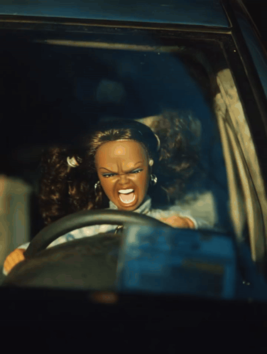 A Doll Is Driving A Car With An Angry Face GIF