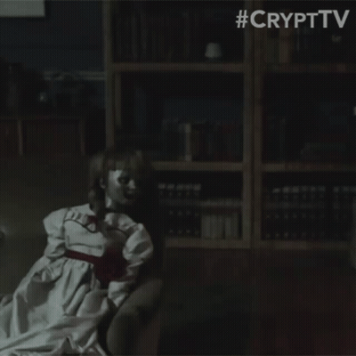 A Doll Is Sitting In A Dark Room With A Bookshelf In The Background . GIF