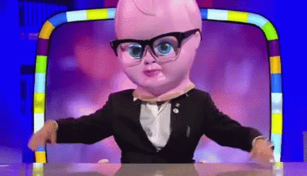 A Doll Wearing Glasses And A Suit Is Sitting At A Desk . GIF