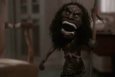 A Doll With A Long Haired Head Is Holding A Spear In A Room . GIF