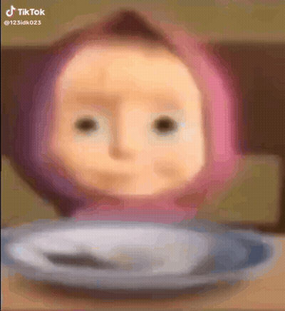 A Doll With A Pink Hat Is Sitting On A Plate With A Spoon . GIF