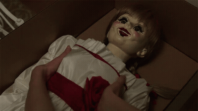 A Doll With A Red Ribbon Around Her Waist Is Laying In A Box GIF