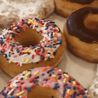 A Donut With Pink Frosting And Sprinkles On Top GIF