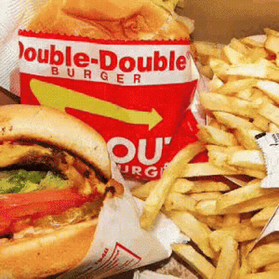 A Double-Double Burger And French Fries Are Sitting On A Table GIF