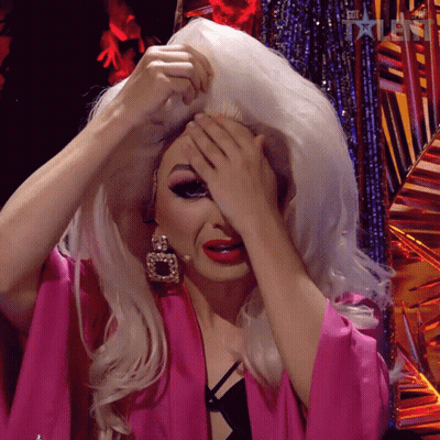 A Drag Queen Covering Her Face With Her Hands While Wearing A Pink Kimono GIF
