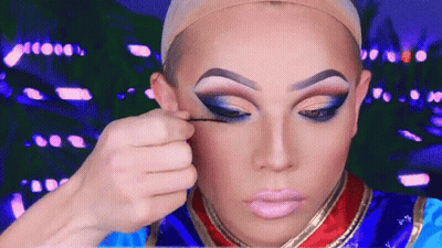 A Drag Queen Is Applying Makeup To Her Eyes GIF