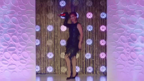 A Drag Queen Is Dancing On A Stage With A Microphone In Her Hand GIF