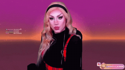 A Drag Queen Is Giving A Kiss In Front Of A Screen That Says ' Neueslacok ' On It GIF