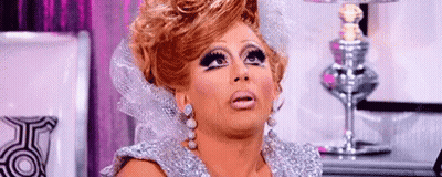A Drag Queen Is Making A Funny Face In Front Of A Lamp . GIF
