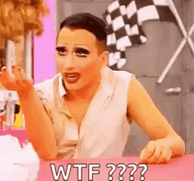 A Drag Queen Is Sitting At A Table Making A Funny Face And Saying `` Wtf '' . GIF