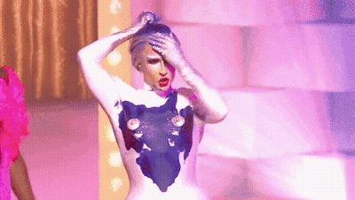 A Drag Queen Is Standing On A Stage With Her Hands On Her Head And A Purple Background . GIF
