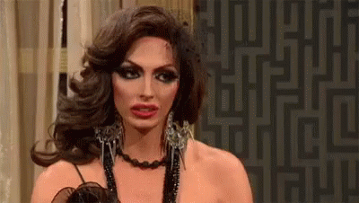 A Drag Queen Is Wearing A Necklace And Earrings And Making A Face . GIF