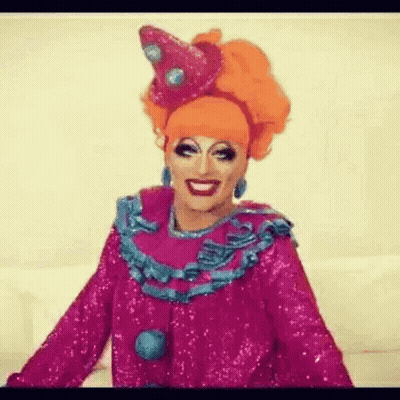 A Drag Queen Is Wearing A Pink And Blue Clown Costume . GIF