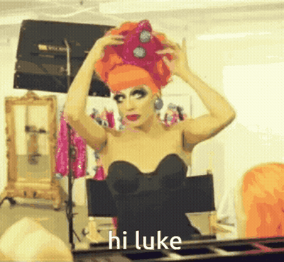 A Drag Queen Says Hi Luke While Putting On A Crown GIF