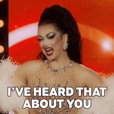 A Drag Queen Says " I 'Ve Heard That About You " In Front Of A Red Background GIF
