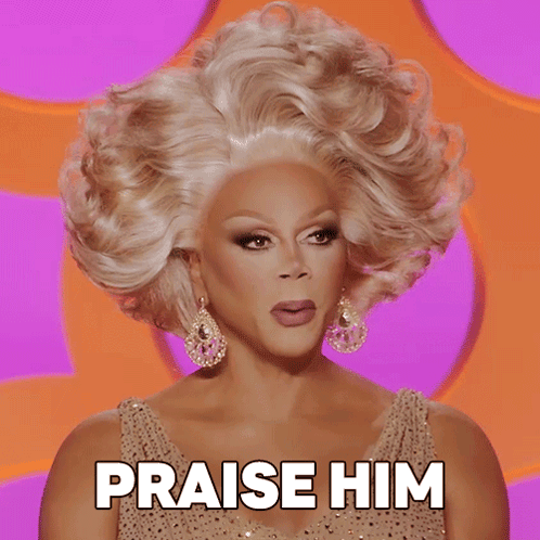 A Drag Queen Says Praise Him In Front Of A Pink Background GIF