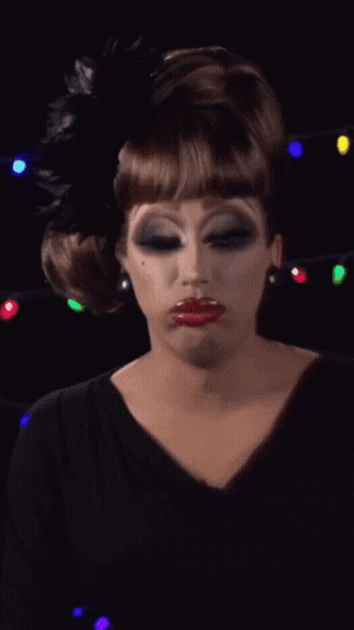 A Drag Queen Wearing A Black Dress And A Black Feather In Her Hair GIF