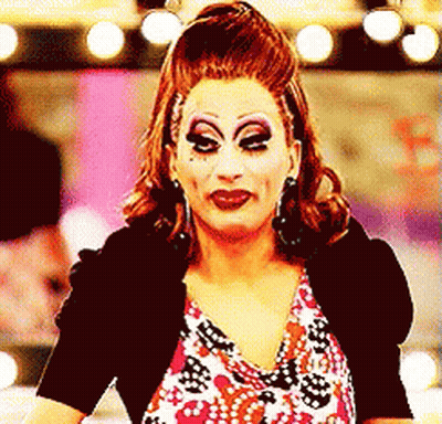 A Drag Queen Wearing Makeup And A Black Jacket GIF