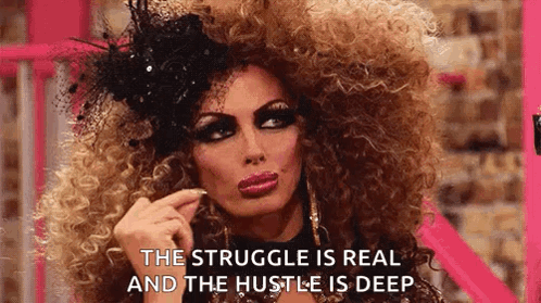 A Drag Queen With A Big Curly Hair And A Hat Is Making A Funny Face . GIF