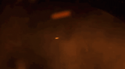 A Dragon Is Flying Through The Air In Front Of A Fire . GIF
