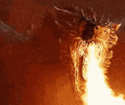 A Dragon Is Flying Through The Air With A Lot Of Fire Coming Out Of Its Mouth . GIF