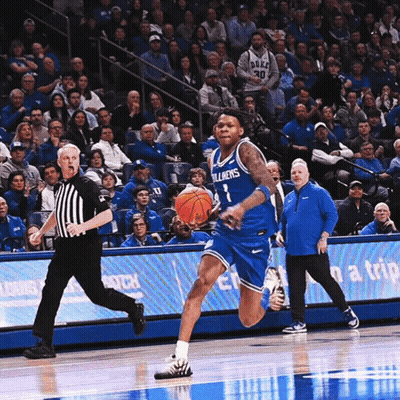 a duke basketball player dribbles the ball while a referee watches