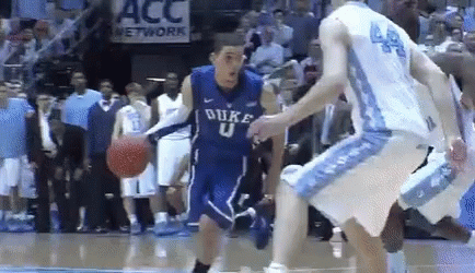 A Duke Basketball Player Is Dribbling The Ball While Another Player Tries To Stop Him GIF